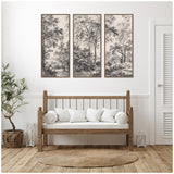 Three-panel black and white tree landscape artwork in wooden frames above a wooden bench with cream cushions, flanked by potted plant and white lantern on light wood floor