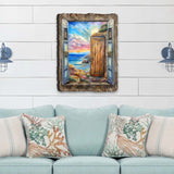 Wall art featuring an open blue window frame and rustic wooden door revealing a colorful coastal sunset over a rocky shore, mounted on a white shiplap wall above light blue sofa with coral-patterned pillows.