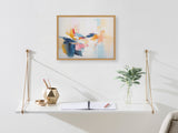 Minimalist white suspended shelf with gold rope supports holding a geometric gold container, open notebook, and clear vase with eucalyptus, beneath colorful abstract wall art.