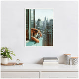Framed canvas of a tiger leaning over a rooftop ledge with a city skyline in the background, displayed on a white wall above a minimalist desk with decor.