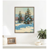 Framed canvas print of two snow-capped evergreen trees casting blue shadows on snow, with serene mountains and pale sky in the background, hanging above a white shelf.