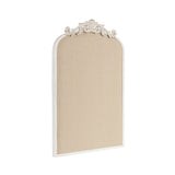 Beige fabric pinboard with a white arched frame and ornate decorative scrollwork at the top center.