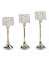 Set of three silver-tone aluminium candle holders with square tops adorned with multiple clear crystal-like beads, varying in height from short to tall.