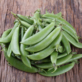 Cluster of fresh, plump green sugar snap pea pods with stems, arranged on a textured wooden surface showing natural grain and weathering.