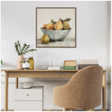 Still life painting of pears and an orange arranged in a white bowl with a pear placed outside, framed in a simple brown wooden frame on a white wall.
