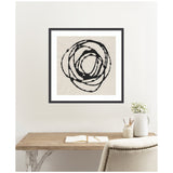 Minimalist black circular swirl abstract artwork in black frame on beige canvas, hanging above a wooden desk with open notebook, white vase, and pencils.
