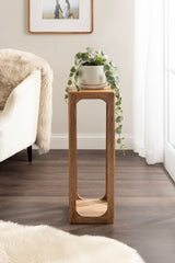 Tall, narrow Dahl Square wood tea table with smooth edges and open sides, holding a potted trailing plant in a silver pot by a bright window and light furniture.
