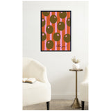 Framed canvas print featuring olive green circles with pink star accents on vertical pink and orange stripes, signed in black cursive at bottom right, hanging on white wall above brass side table and two cream armchairs.