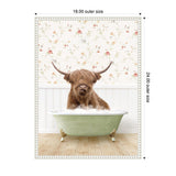 Highland cow with long shaggy hair and large curved horns sitting in a pale green clawfoot bathtub filled with bubbles against a floral wallpaper and white wainscoting background.