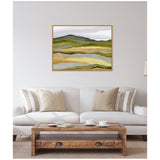 Abstract landscape painting with layered green, yellow, and earthy tones in a wooden frame above a beige sofa with striped and solid pillows in a neutral living room.