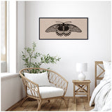 Black detailed butterfly print on a neutral textured linen panel, framed and hung above a white cushioned rattan chair next to a wooden side table with a white lamp in a bright room.