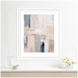 Framed abstract painting with rectangular blocks in muted tones of blue, beige, blush, and gray on a white wall above a minimalist white shelf with glass and ceramic decor and a small floral arrangement.