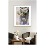 Soft pastel-toned painting of a hanging bouquet with white, pink, and peach flowers in a silver frame above a cozy seating area with gray chairs and a round wooden table.