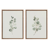Two framed canvas artworks each featuring a single eucalyptus branch with soft green leaves on a white background, bordered by brown frames with beaded detailing.