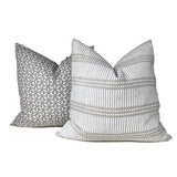 Two decorative throw pillows: one with a geometric floral pattern in muted gray tones, and the other with horizontal stripes and dots in chalk and soft gray.