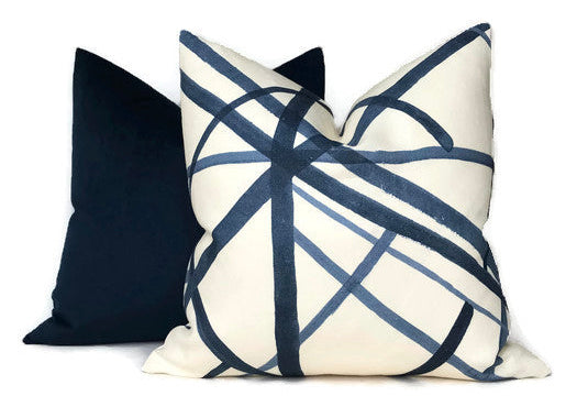 Two square pillow covers, one solid dark navy and the other white with overlapping navy blue abstract curved lines, positioned side by side.