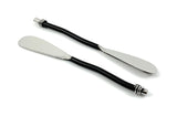 Set of six Vibhsa black silverware butter spreaders resting on a wooden surface alongside cheese and crackers
