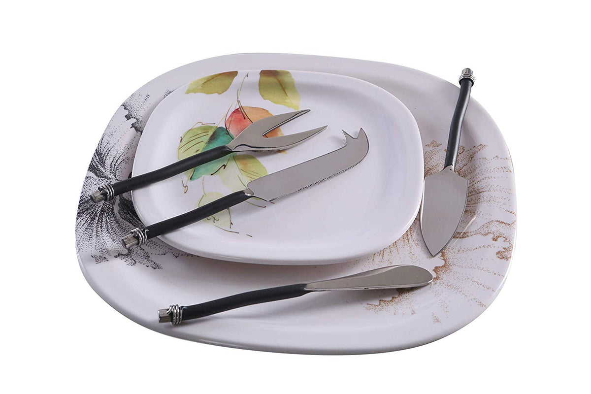 Set of four stainless steel cheese knives with black curved handles arranged on two white decorative plates with floral and botanical designs.