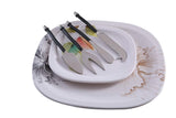 Set of four stainless steel cheese knives with black curved handles resting on two decorative ceramic plates with floral patterns in black and brown.