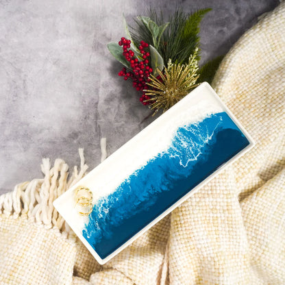 Rectangular resin ceramic tray with blue wave design on a textured surface with greenery and berries.