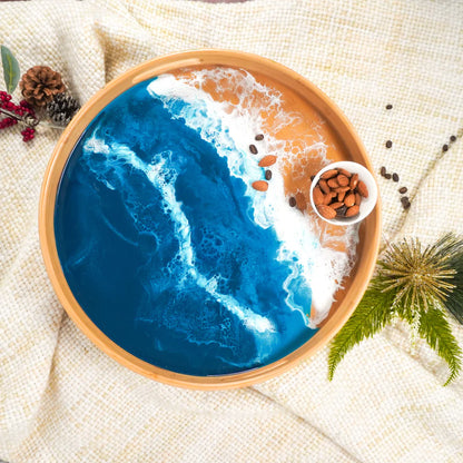 Decorative resin serving tray with blue ocean design and wooden rim on a textured surface.