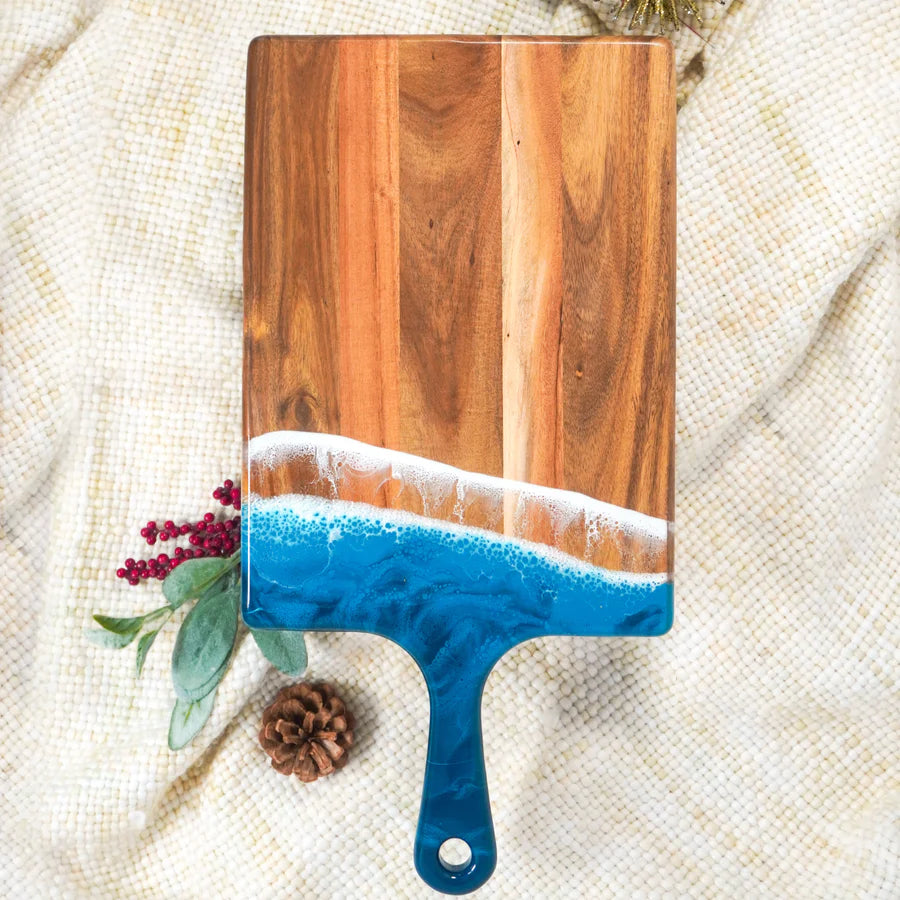 Wooden resin charcuterie board with blue handle on a textured fabric background