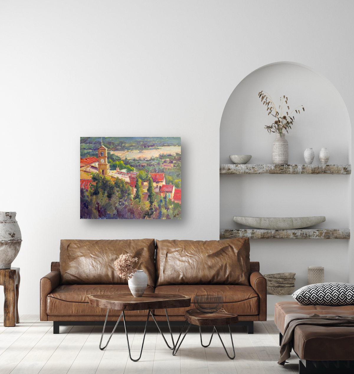 Colorful canvas painting of a clock tower overlooking red-roofed buildings and green trees, displayed above a brown leather sofa in a minimalist living room.