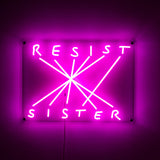 Pink neon LED sign mounted on a wall, displaying the words 'RESIST' and 'SISTER' connected by crisscrossing lines on a rectangular clear backing.