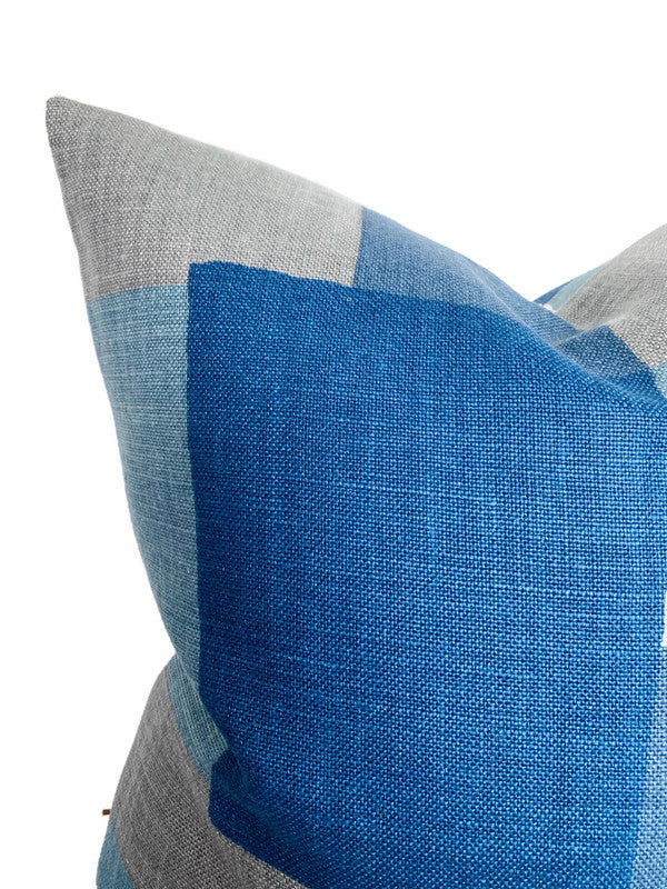 Close-up of a pillow corner featuring a color-blocked pattern with indigo blue, light blue, and gray woven fabric sections.
