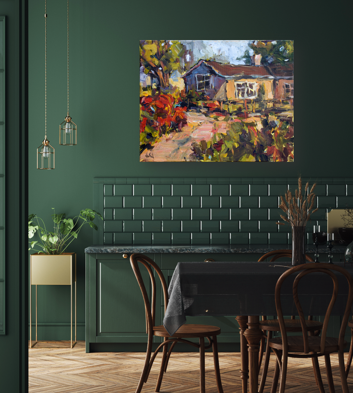 Impressionist canvas painting of a cottage with red flowers and greenery, hanging on a dark green wall above a dining table with bentwood chairs.