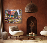Living room with terracotta textured walls, featuring a colorful cottage painting with blue shutters, two cream curved chairs, and a wooden geometric pendant light.