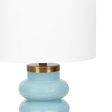 Table lamp with a glossy light blue ceramic base featuring rounded, stacked shapes and a brass-colored metal accent beneath a large white fabric drum shade