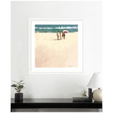 Framed print of three people walking on a sandy beach toward blue-green ocean under a partly cloudy sky, one holding a colorful umbrella, signed by Mary Sparrow.