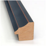 Close-up of a black wooden picture frame molding with a smooth matte finish and subtle reddish-brown edges, showing its angled cross-sectional profile.