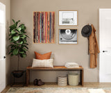 Three framed artworks above a wooden bench with pillows, showing colorful vertical lines, a black-and-white record player sketch, and a black-and-white close-up of a vinyl record and needle.