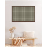 Wall-mounted pinboard with sage green plaid fabric and wooden frame above a minimalist wooden bench with white pillows and a beige throw beside a white vase with dried flowers.