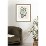 Framed art print of a green striped vase with stylized green flowers and French text 'Les Fleurs' in dark blue, hanging above an olive green armchair and wicker basket with a leafy plant.