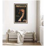 Vintage-style framed poster of an ostrich blowing bubbles with a pipe, advertising Prosecco on a dark background with gold and beige text.