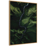 Aerial view of a narrow, winding river cutting through a lush, green valley with steep moss-covered cliffs, captured on a vertical canvas framed in light wood.