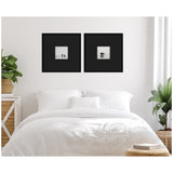 Two black-framed square prints with small black-and-white humpback whale images centered on a white wall above a white bed, flanked by green plants.