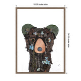 Portrait of a black bear composed of textured wood bark and moss, accented with light blue flower petals and earthy green ears, framed by a simple brown frame.