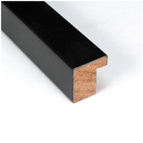 Close-up of a rectangular black picture frame molding with a stepped inner profile and exposed wood grain on the cut end, shown on a white background.
