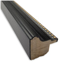 Close-up of a black wood picture frame molding with a gold beaded decorative detail along the inner edge, showing the cross-section of the frame profile.