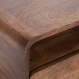 Close-up of a wooden corner with smooth rounded edges and visible circular grain patterns on the surface, showing a small open storage space beneath the top panel.