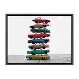 Eight vintage toy cars stacked vertically in varied colors including red, yellow, green, blue, and brown, set against a white background on wood grain surface.