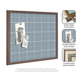 Rectangular pinboard with light blue plaid fabric and thin white grid lines, framed in medium brown wood, holding two black-and-white photos attached with push pins.