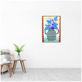 Framed canvas print of a stylized blue and purple fig plant with patterned blue-green pot and red scalloped border, hanging on a white wall above wooden table and plant.