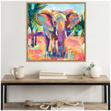 Colorful painting of an African elephant in bright orange, pink, and blue hues with palm trees, framed and hanging above a wood and metal console table.