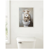 Framed artwork of a fluffy white sheep holding a toilet paper roll, sitting on a toilet seat against a gray background above a white toilet tank.