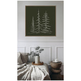 Minimalist framed canvas with white line sketches of three evergreen trees on dark green background hanging above a cozy neutral-toned living room setup with textured blanket and wood stool.